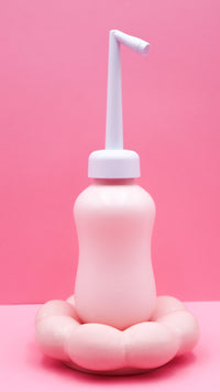 Douchette nomade intime rose, embout blanc vertical et base arrondie