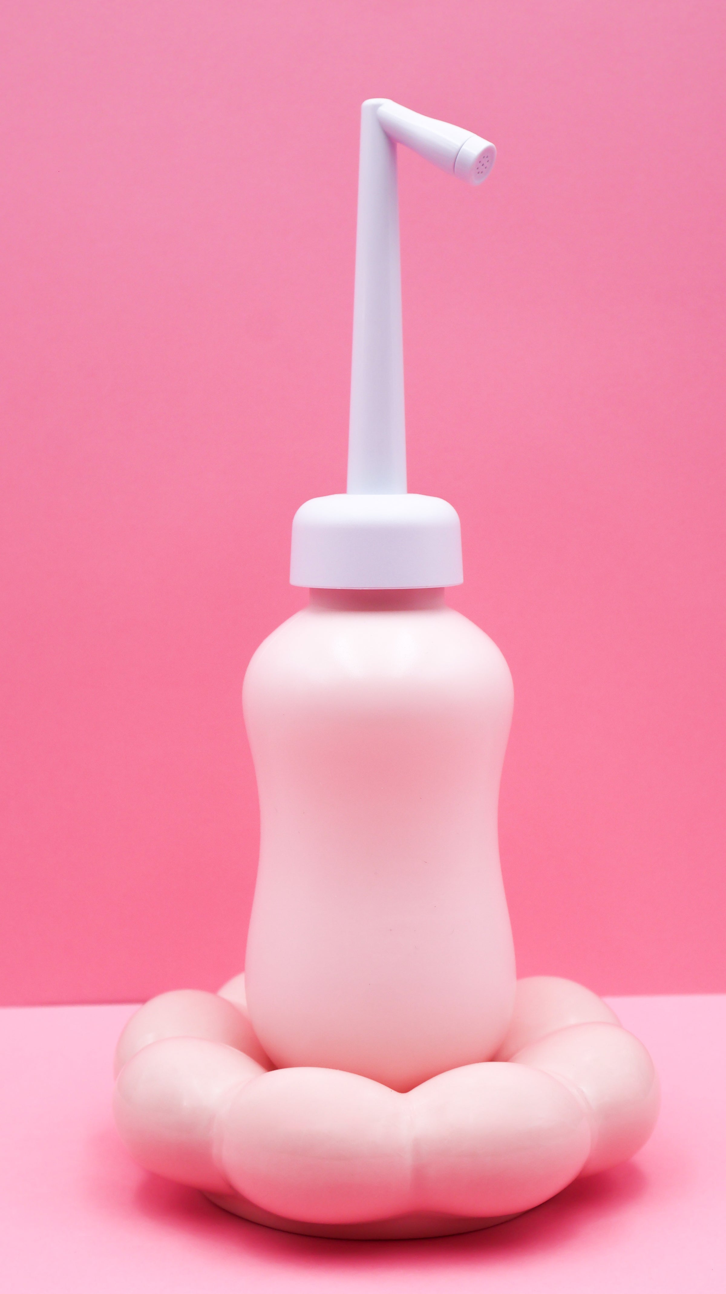 Douchette nomade intime rose, embout blanc vertical et base arrondie
