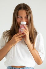 Gummies probiotiques : femme tenant un flacon rouge de gummies.
