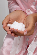 Mousse blanche onctueuse dans les mains, pour nettoyage intime