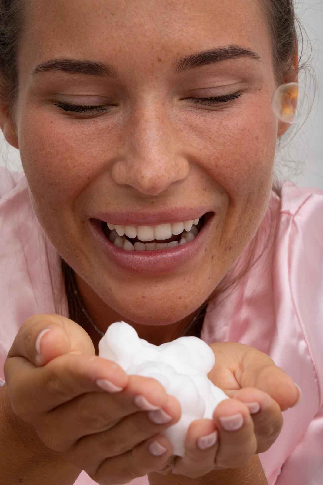 Mousse blanche dans les mains, geste de nettoyage avec mousse intime