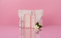 Pack Les Essentielles : 3 flacons et une bouteille rose pâle, sur trousse blanche