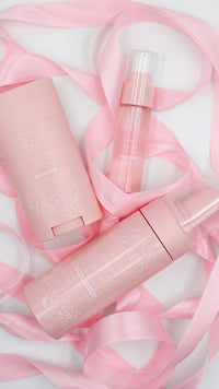 Pack Les Essentielles : flacons et tubes cosmétiques roses, avec ruban rose