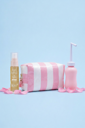 Pack nomade Zawaj Secret's avec gel parfumé, trousse rayée et douchette rose sur fond bleu ciel